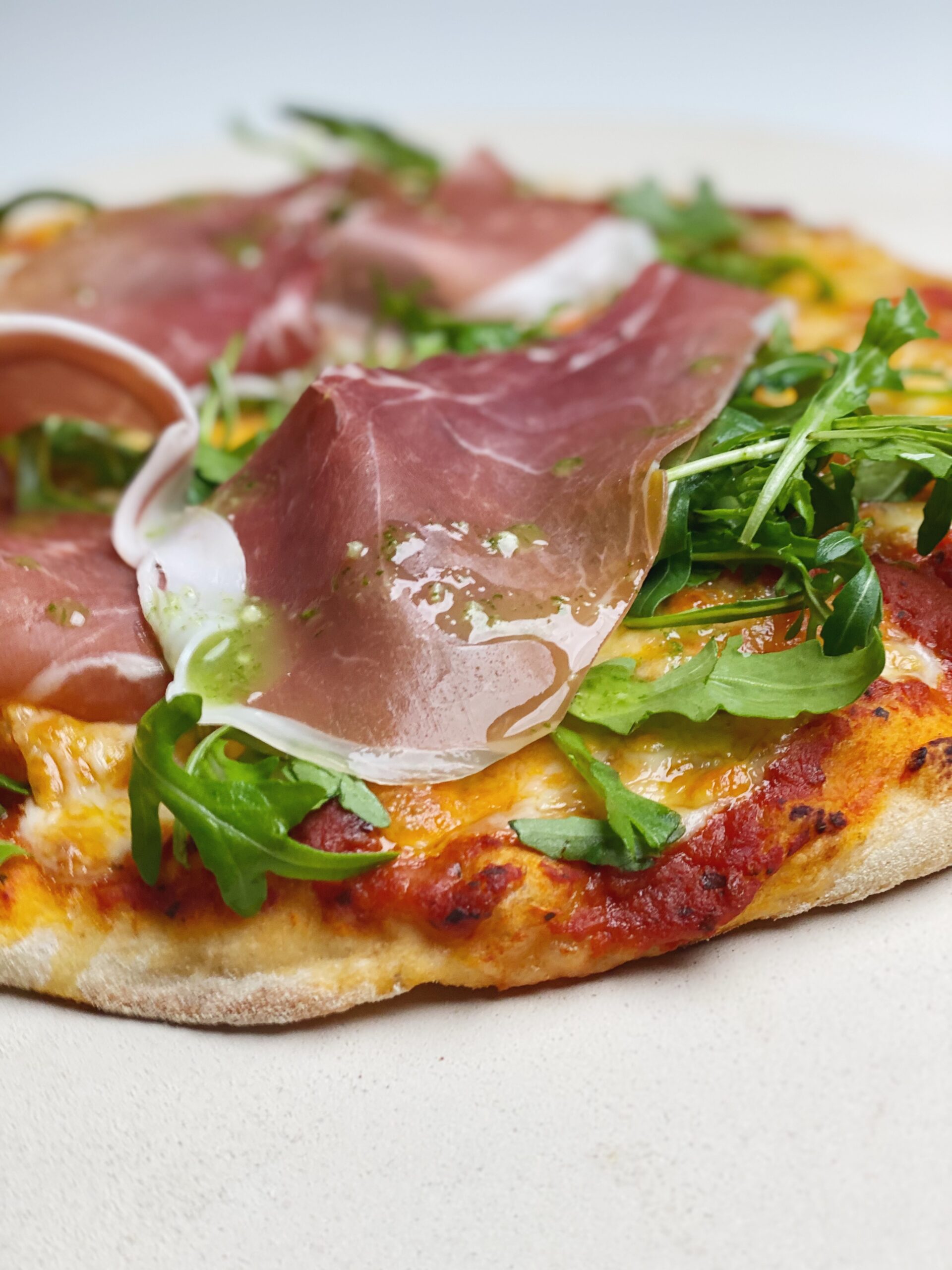 Grov pizza med rucola, parmaskinke og hvidløgsolie