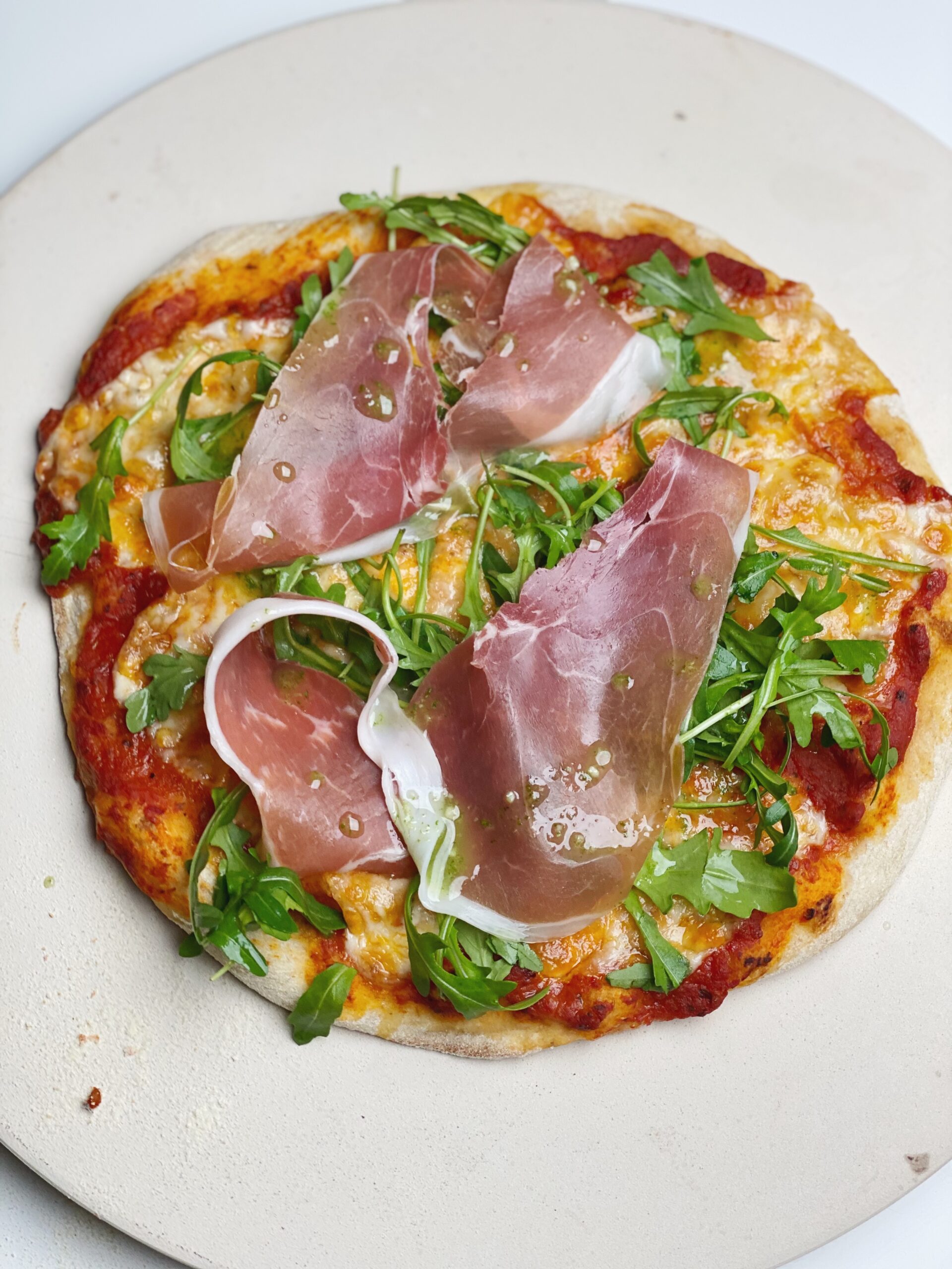 Grov pizza med rucola, parmaskinke og hvidløgsolie