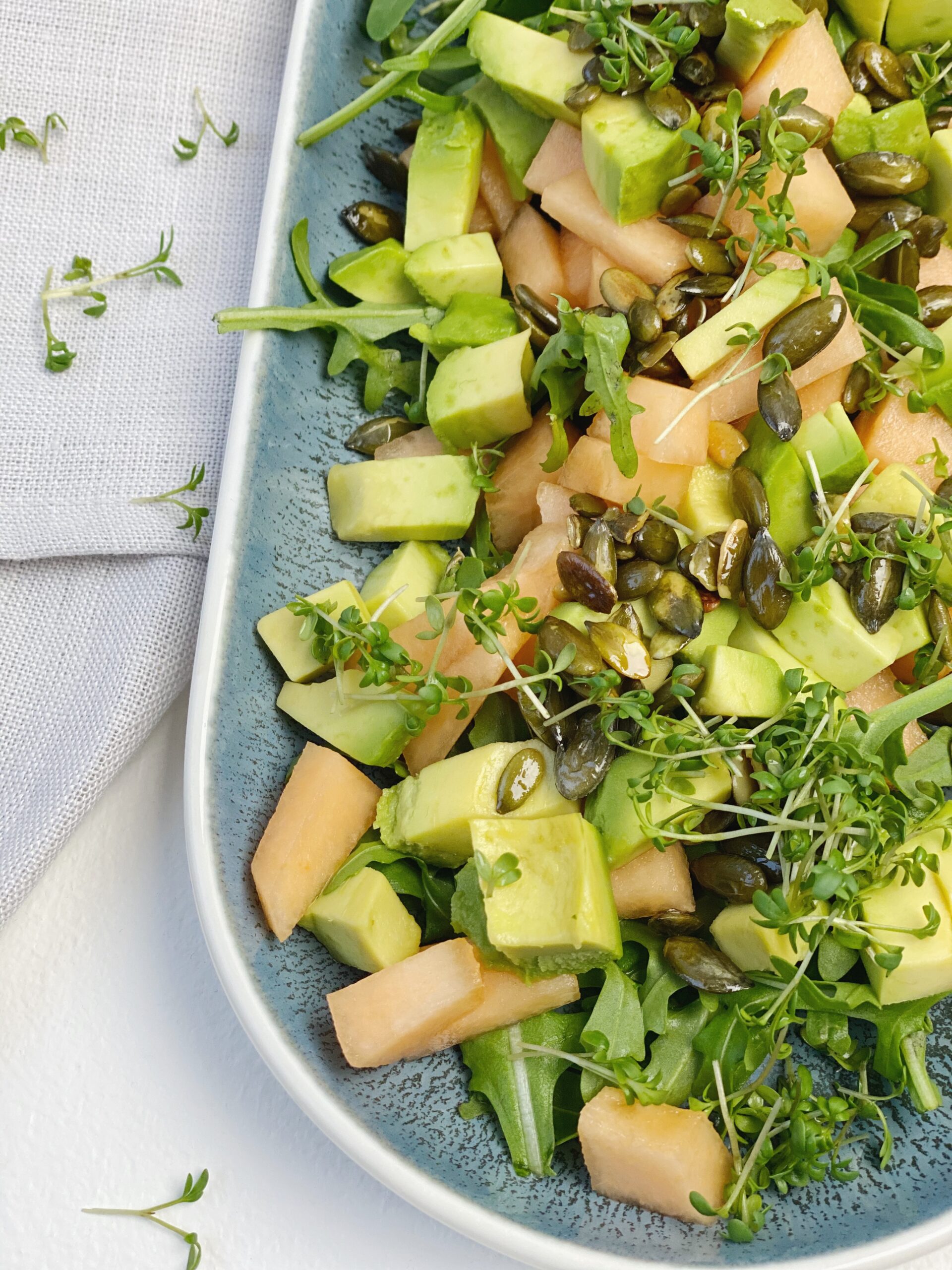 Rucolasalat med avocado, galiamelon, karse og græskarkerner close up